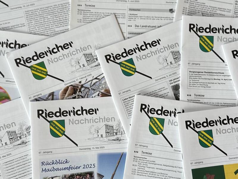 Mehrere Exemplare der "Riedericher Nachrichten" liegen verstreut auf einer Oberfläche.