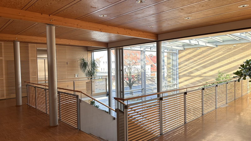 Ein lichtdurchfluteter Innenraum eines modernen Gebäudes mit Holzelementen und einer großen Glasfläche .